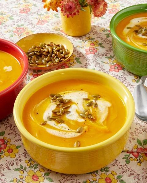 pumpkin soup in yellow bowl with seeds and cream