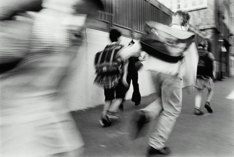 Schoolchildren (10-12) running along street (blurred motion, B&W)