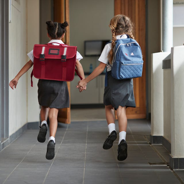 Schoolgirls running hand in hand on the isle of school and laughing