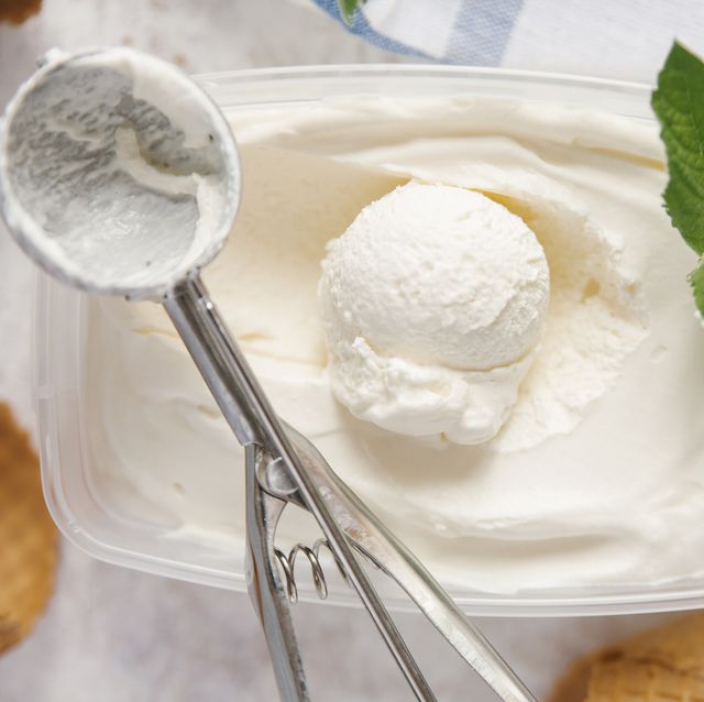 Scoop of ice cream in container with mint near cones