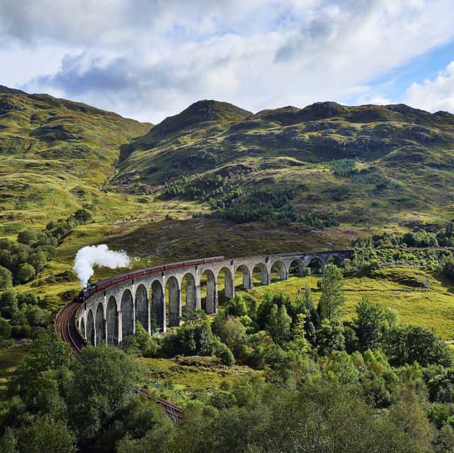 uk, scotland, highlands, glenfinnan viaduct with a steam train passing over it