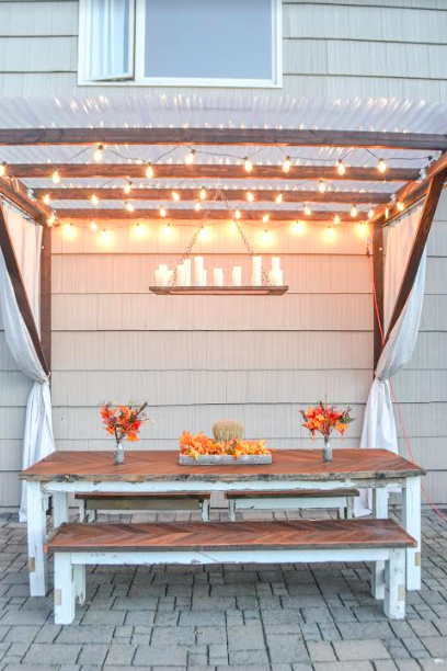 wooden bench seating  with table under a pergola and glowing lights