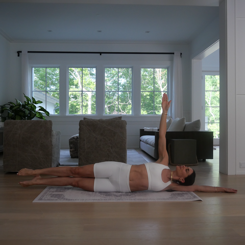 woman in a white workout outfit on the floor exercising her inner thighs