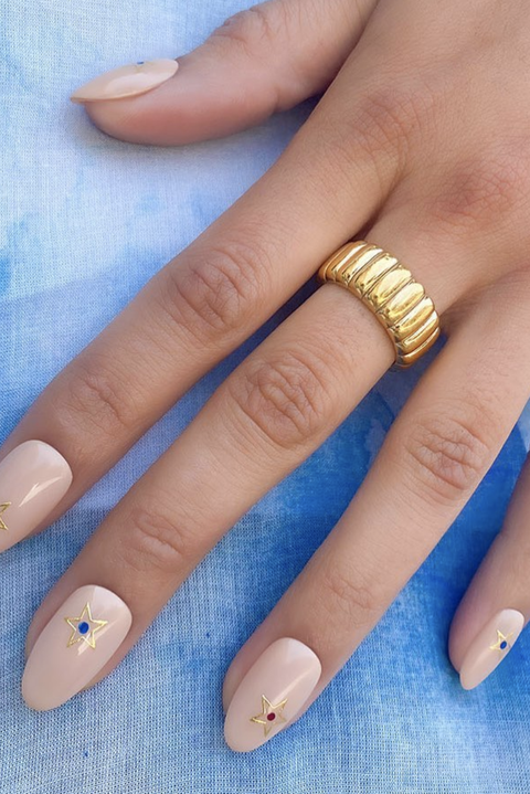 a nude manicure with gold stars on a blue background