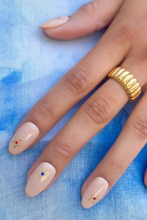 a nude manicure with gold stars on a blue background