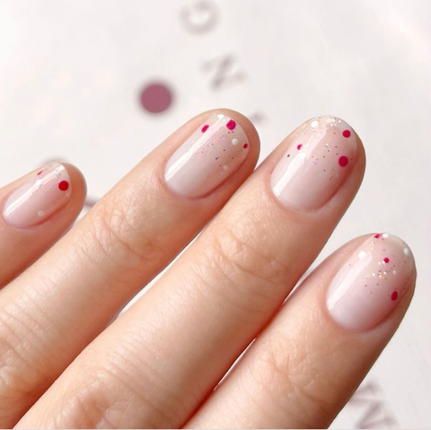 nude nails with firework nail glitter with pink, gold and white polka dots
