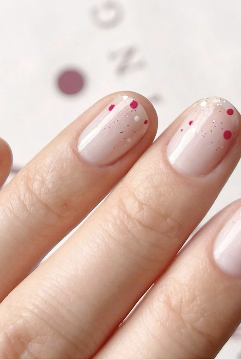 nude nails with firework nail glitter with pink, gold and white polka dots