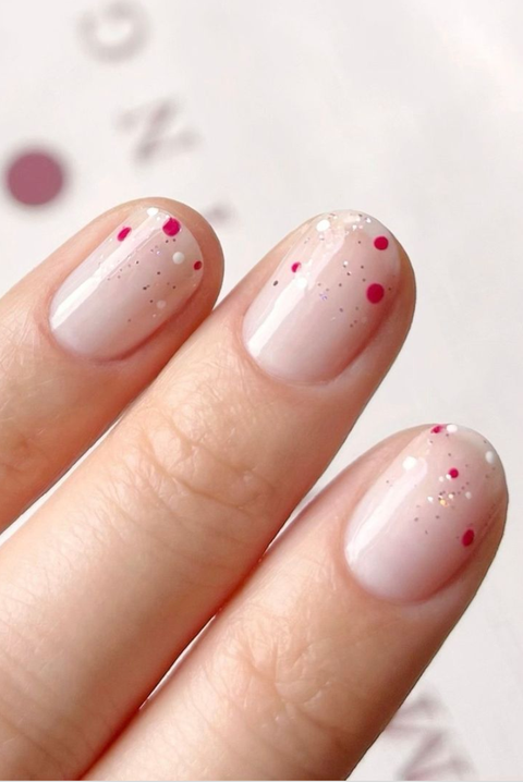 nude nails with firework nail glitter with pink, gold and white polka dots