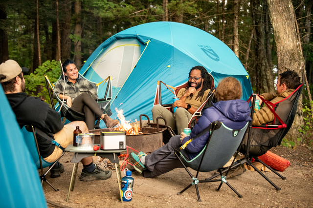 people sitting around fire in camping chairs