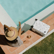 person sitting at pool with suitcase next to them
