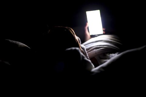 Woman using smartphone for looking up social medial at late night lying in bed, Internet addicted.