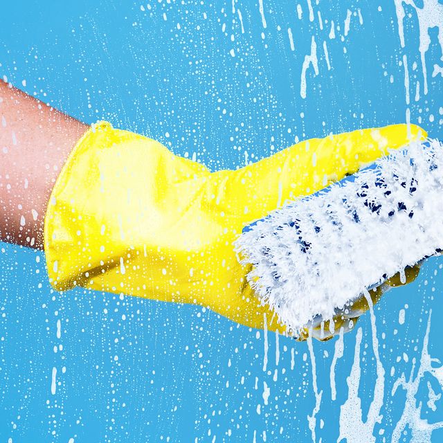 hand in yellow rubber glove using blue scrub brush