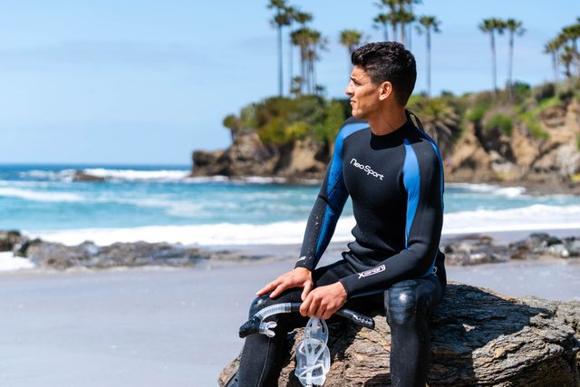 man wearing scuba gear sitting by ocean
