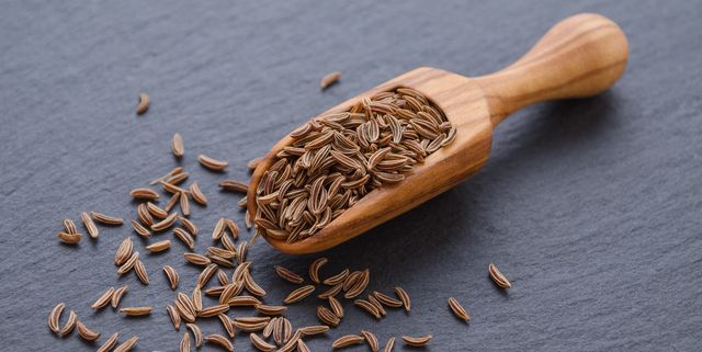 seeds of cumin, caraway in a wooden scoop on black background