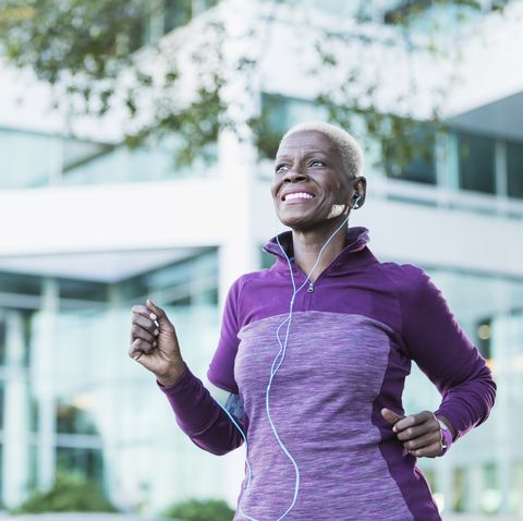 senior african american woman exercising outdoors with earphones in