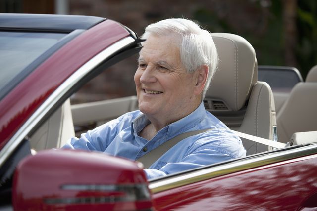 a senior man driving a convertible sports car