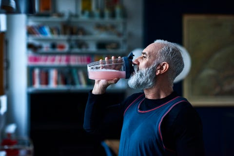 Senior man wearing sports top gulping health drink from container