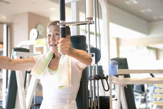 senior woman exercising on machine in gym