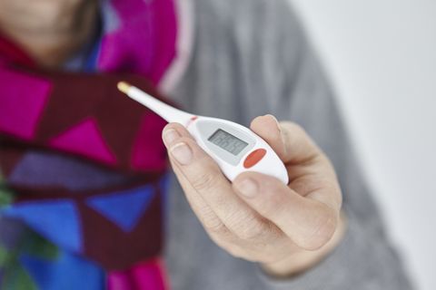 senior woman holding digital thermometer, close up