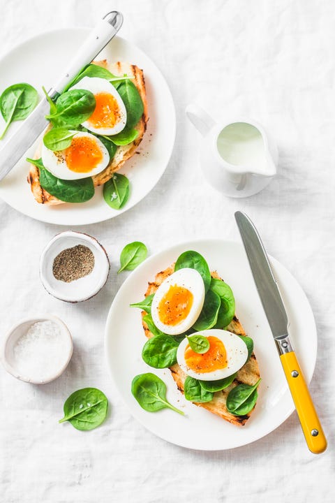 Served Easter brunch plate - grilled bread sandwich with spinach and boiled eggs on white background, top view Served Easter brunch plate - grilled bread sandwich with spinach and boiled eggs on white background, top view