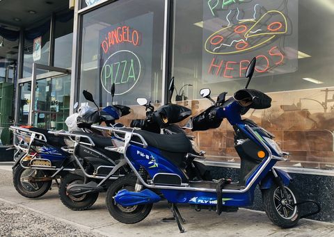 several electric scooters used for food delivery parked in front of d'angelo pizza and hero restaurant, queens, new york