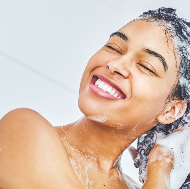 woman sudsing shampoo in hair in shower