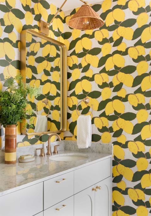 powder room, lemon art wallpaper, white cabinets, marble countertops, gold faucet, gold mirror, rattan lamp shade