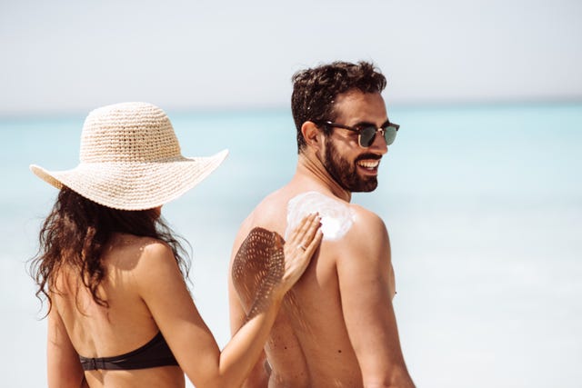 woman putting sun screen on a mans back