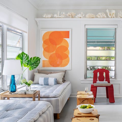 A List 2022 - ELLE DECOR herb sambol’s 1920s palm beach bungalow, renovated by the architect lee f mindel in the living room, a side table by serena lily separates a pair of daybeds by hästens, the vintage molded plywood chair is by robert venturi and denise scott brown for knoll, and thevintage stools are by barry simpson a collection of coral lines a high shelf above artwork by thomas trum