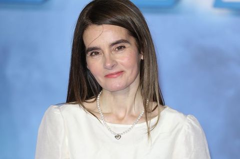 Shirley Henderson, on a blue blurred background, wearing a white top