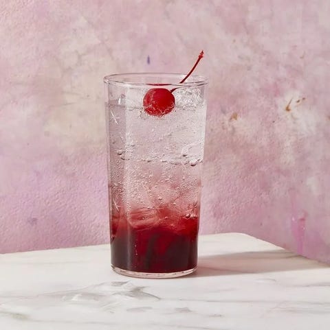 a glass of shirley temple with a cherry on top