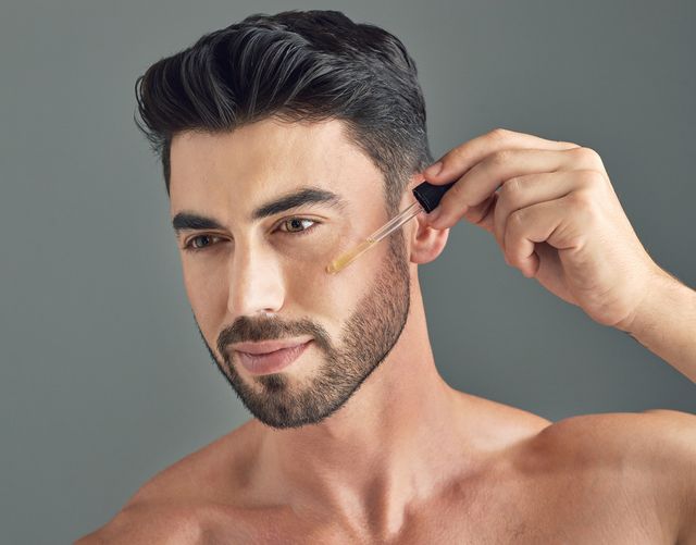 shot of a handsome young man applying serum to his face with a dropper