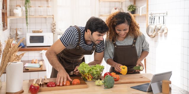 shot of a happy young couple using a digital tablet while preparing a healthy meal together at home