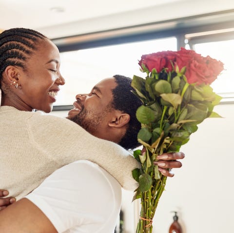 Shot of a young man surprising his wife with a bunch of flowers at home