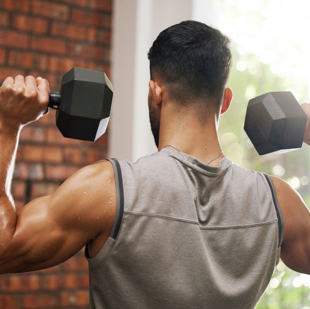 shot of a young man working out with dumbbells in a gym