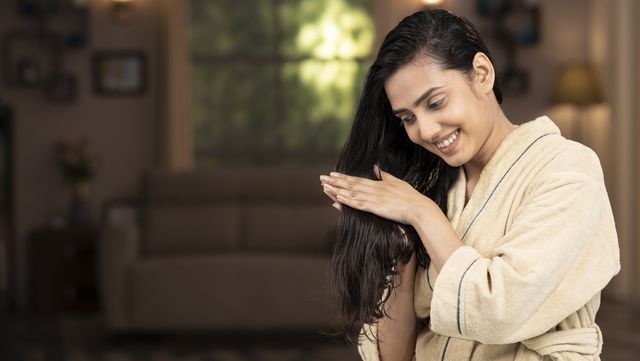 shot of a young women in bathrobe doing hair massage at home
