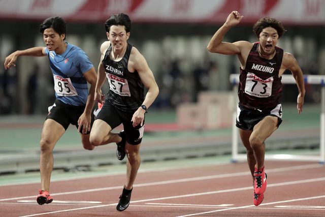 tres atletas japoneses esprintan y uno celebra su victoria en una carrera en el verano de 2020