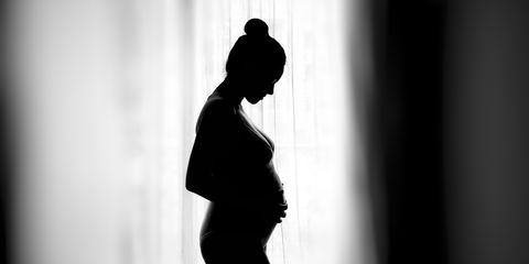 Side View Of Silhouette Pregnant Woman Standing By Window At Home