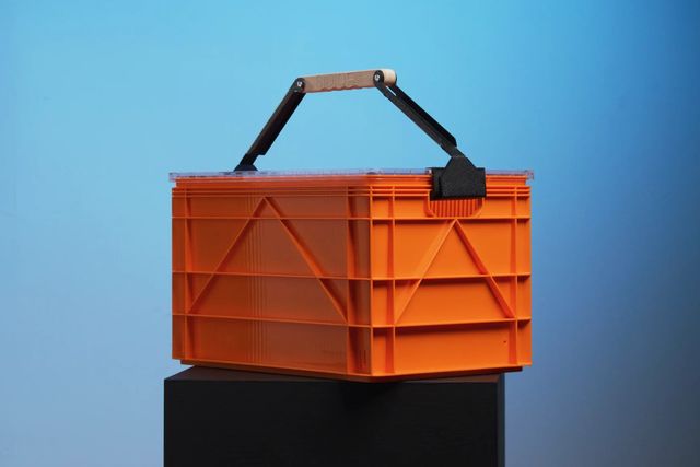 an orange sidio milk crate on a black pedestal