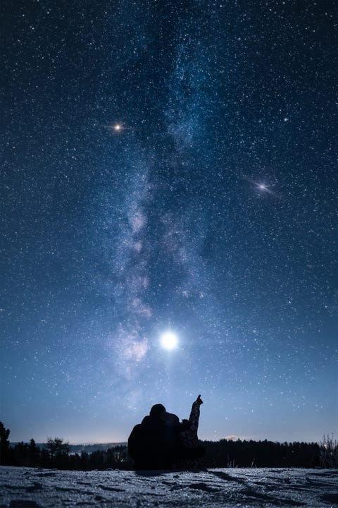 silhouette couple sitting on mountain against star field at night