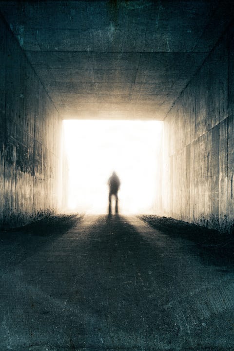 A silhouette of a blurred figure emerging from the light at the end of a dark sinister tunnel. With a grunge, vintage, grainy edit. a silhouette of a blurred figure emerging from the light at the end of a dark sinister tunnel with a grunge, vintage, grainy edit