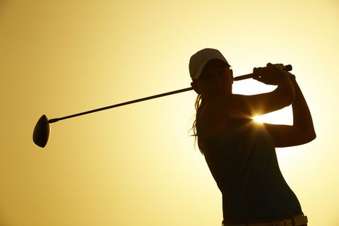 Silhouette of woman playing golf on course