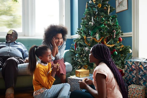 a black woman and two black girls sitting in front of a christmas tree with a pad of paper and a pen