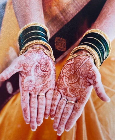 a woman's open palms covered in intricate mehendi designs and gold jewelry