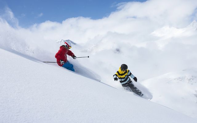 skier and snowboarder on snowy slope