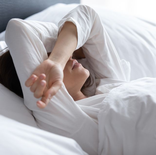 sleepless young woman suffering from insomnia, covering eyes with hands
