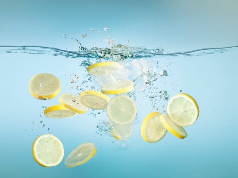 Sliced lemons splashing in water - lemon water