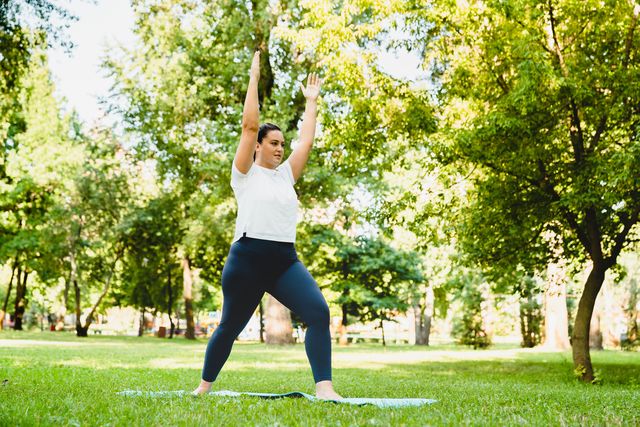 slimming burning calories exercises caucasian plump young woman athlete in fitness clothes doing yoga on fitness mat outdoors in park