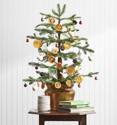 a sparse alpine balsam fir channels a less is more mentality, while an antique copper pot anchors the display with metallic heft and bird and pine cone ornaments and a dried orange garland hit an organic note