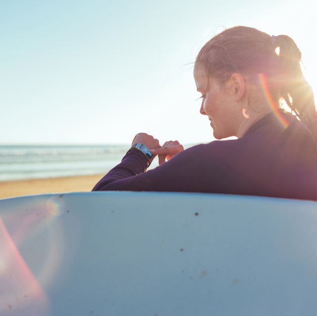 woman checking smartwatch on the beach in sunlight